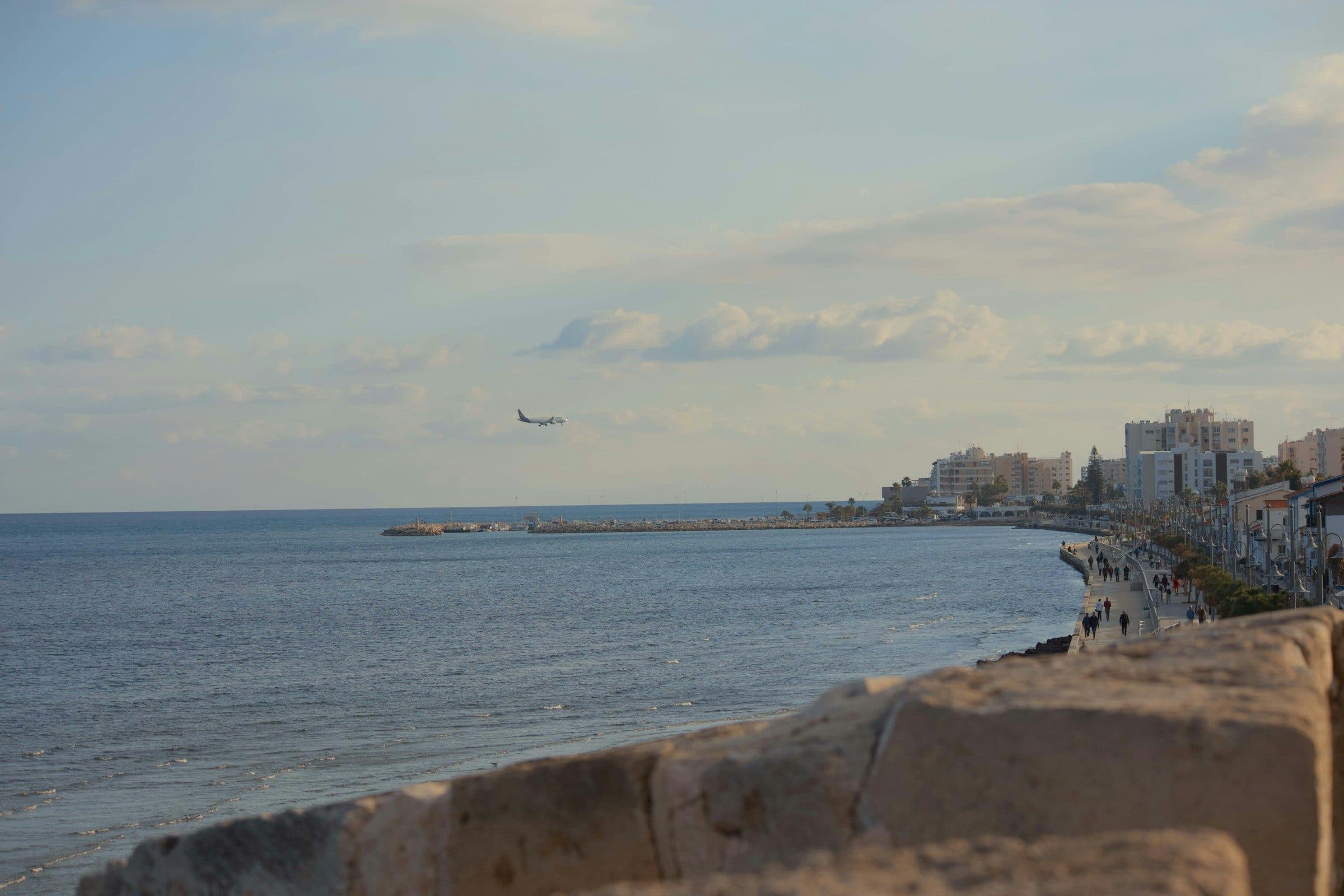 Blick von der Uferpromenade in Larnaca auf das Meer, ein Flugzeug im Landeanflug